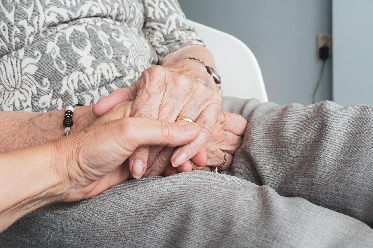 Caring hands holding elderly persons hands in comfort